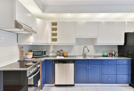 a-kitchen-with-blue-cabinets-and-a-black-refrigerator