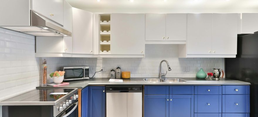 a-kitchen-with-blue-cabinets-and-a-black-refrigerator