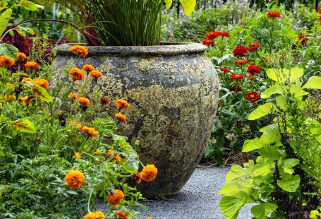 a-large-vase-sitting-in-the-middle-of-a-garden-filled-with-flowers